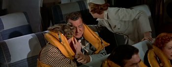 Movie still from “The High and the Mighty” (1954), directed by William A. Wellman – An older man is holding an orange life jacket over his face; Medium shot, High angle