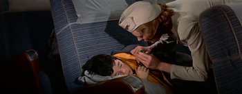 Movie still from “The High and the Mighty” (1954), directed by William A. Wellman – An older woman is helping a young boy with a bandage; Medium shot, Overhead angle