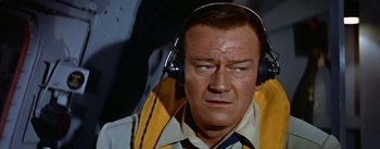 Movie still from “The High and the Mighty” (1954), directed by William A. Wellman – An older man wearing headphones while looking at the camera; Close Up shot, High angle