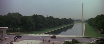 Movie still from “The Hindenburg” (1975), directed by Robert Wise – A car driving down a street next to a body of water; Extreme Wide shot, High angle