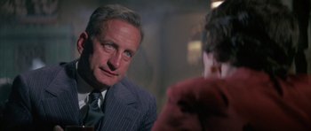 Movie still from “The Hindenburg” (1975), directed by Robert Wise – A person wearing a suit and a tie; Close Up shot, Over the shoulder angle