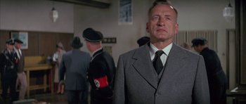 Movie still from “The Hindenburg” (1975), directed by Robert Wise – A man in a suit and tie standing in front of other men; Close Up shot, Low angle