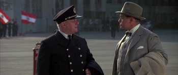 Movie still from “The Hindenburg” (1975), directed by Robert Wise – A man in a military uniform talking to another man; Medium shot, Over the shoulder angle