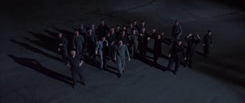 Movie still from “The Hindenburg” (1975), directed by Robert Wise – A group of men standing next to each other in the dark; Wide shot, High angle