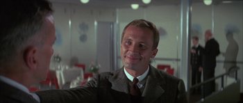Movie still from “The Hindenburg” (1975), directed by Robert Wise – A man wearing a suit and tie smiling for the camera; Close Up shot, Low angle