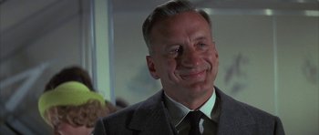 Movie still from “The Hindenburg” (1975), directed by Robert Wise – A man in a suit and tie smiling for the camera; Close Up shot, Low angle