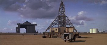 Movie still from “The Hindenburg” (1975), directed by Robert Wise – An old truck parked in front of an oil rig; Extreme Wide shot, Low angle