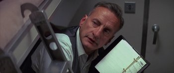 Movie still from “The Hindenburg” (1975), directed by Robert Wise – An older man looking at the camera in a mirror; Close Up shot, Low angle