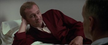 Movie still from “The Hindenburg” (1975), directed by Robert Wise – A man in a red robe laying on a bed; Close Up shot, Low angle
