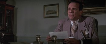Movie still from “The Hindenburg” (1975), directed by Robert Wise – A man sitting at a table holding a piece of paper; Close Up shot, Low angle
