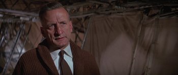 Movie still from “The Hindenburg” (1975), directed by Robert Wise – An older man wearing a sweater and a tie; Close Up shot, Low angle