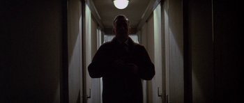 Movie still from “The Hindenburg” (1975), directed by Robert Wise – A man standing in a dark hallway with a light on; Medium shot, Low angle