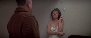 Movie still from “The Hindenburg” (1975), directed by Robert Wise – A woman is putting lipstick on a man's face in front of a bathroom mirror; Close Up shot, Over the shoulder angle