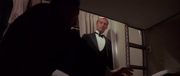 Movie still from “The Hindenburg” (1975), directed by Robert Wise – A man in a tuxedo looking at himself in the mirror; Medium shot, Low angle