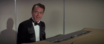 Movie still from “The Hindenburg” (1975), directed by Robert Wise – A man in a tuxedo sitting at a piano; Close Up shot, Low angle