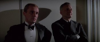 Movie still from “The Hindenburg” (1975), directed by Robert Wise – A man in a suit and tie next to another man in a suit and tie; Close Up shot, Low angle