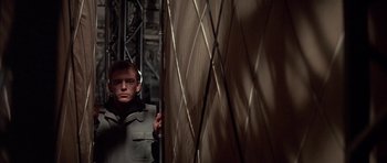 Movie still from “The Hindenburg” (1975), directed by Robert Wise – A man standing next to a wall in a room; Medium shot, Low angle