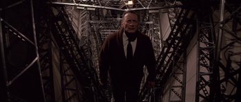Movie still from “The Hindenburg” (1975), directed by Robert Wise – An older man in a suit and tie standing in the middle of a bridge; Medium shot, Low angle