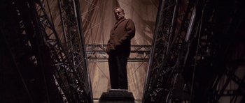 Movie still from “The Hindenburg” (1975), directed by Robert Wise – A man in a brown suit standing on a platform; Wide shot, Low angle