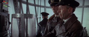 Movie still from “The Hindenburg” (1975), directed by Robert Wise – A group of men standing next to each other in a room; Medium shot, Low angle