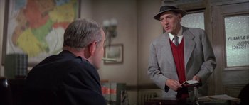 Movie still from “The Hindenburg” (1975), directed by Robert Wise – A man in a suit and hat talking to another man in a suit; Medium shot, Over the shoulder angle