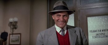 Movie still from “The Hindenburg” (1975), directed by Robert Wise – A man wearing a suit and a hat smiling for the camera; Close Up shot, Low angle