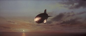 Movie still from “The Hindenburg” (1975), directed by Robert Wise – An airship is flying in the sky over the ocean; Extreme Wide shot, Low angle