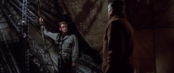 Movie still from “The Hindenburg” (1975), directed by Robert Wise – A man standing next to another man on a boat; Medium shot, Low angle