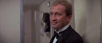 Movie still from “The Hindenburg” (1975), directed by Robert Wise – A man in a tuxedo smiling for the camera; Close Up shot, Low angle