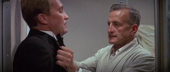 Movie still from “The Hindenburg” (1975), directed by Robert Wise – An older man helping a younger man fix a tie; Close Up shot, Low angle