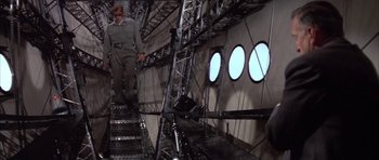 Movie still from “The Hindenburg” (1975), directed by Robert Wise – A man walking up a flight of stairs in an airplane; Wide shot, Low angle