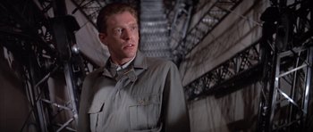 Movie still from “The Hindenburg” (1975), directed by Robert Wise – A man in a military uniform standing next to a metal structure; Close Up shot, Low angle