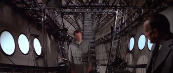 Movie still from “The Hindenburg” (1975), directed by Robert Wise – A man standing in the middle of a room; Wide shot, Low angle
