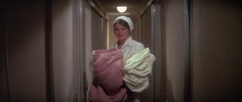 Movie still from “The Hindenburg” (1975), directed by Robert Wise – A woman in a white robe holding a pink pillow; Medium shot, High angle