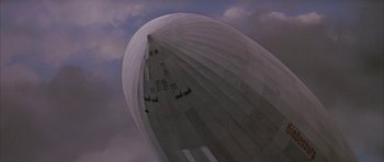 Movie still from “The Hindenburg” (1975), directed by Robert Wise – A large white balloon flying in the sky; Extreme Wide shot, Low angle