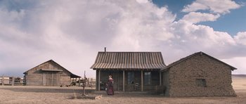Movie still from “The Homesman” (2014), directed by Tommy Lee Jones – A woman standing in front of a wooden house; Extreme Wide shot, Low angle