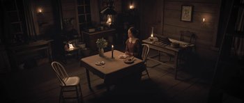 Movie still from “The Homesman” (2014), directed by Tommy Lee Jones – A woman sitting at a table with a candle; Wide shot, High angle