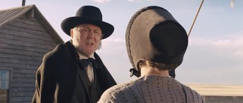 Movie still from “The Homesman” (2014), directed by Tommy Lee Jones – A man wearing a black hat and a black suit; Close Up shot, Over the shoulder angle