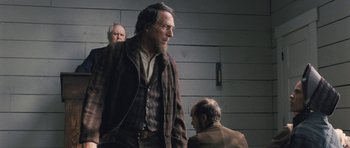 Movie still from “The Homesman” (2014), directed by Tommy Lee Jones – A man with a long beard standing next to another man; Medium shot, Over the shoulder angle