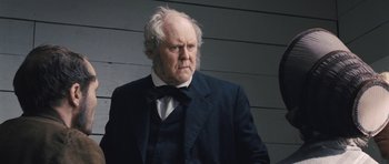 Movie still from “The Homesman” (2014), directed by Tommy Lee Jones – An old man in a black suit and white hair; Close Up shot, Low angle