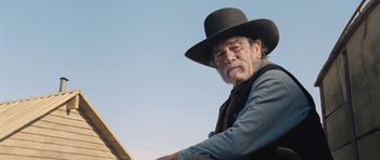 Movie still from “The Homesman” (2014), directed by Tommy Lee Jones – An older man wearing a black hat and a black vest; Medium shot, Low angle