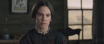 Movie still from “The Homesman” (2014), directed by Tommy Lee Jones – A woman in a black and red dress looking at the camera; Close Up shot, Over the shoulder angle