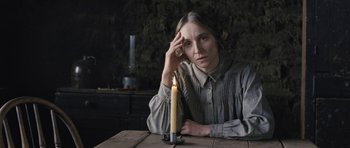 Movie still from “The Homesman” (2014), directed by Tommy Lee Jones – A woman sitting in front of a candle on a wooden table; Close Up shot, High angle