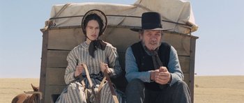 Movie still from “The Homesman” (2014), directed by Tommy Lee Jones – A man and a woman sitting next to each other; Medium shot, High angle