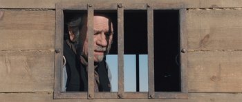 Movie still from “The Homesman” (2014), directed by Tommy Lee Jones – An old man looking out of a jail cell window; Close Up shot, Low angle