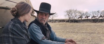 Movie still from “The Homesman” (2014), directed by Tommy Lee Jones – An older man wearing a cowboy hat in a field; Medium shot, Over the shoulder angle