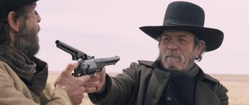 Movie still from “The Homesman” (2014), directed by Tommy Lee Jones – An older man holding a gun pointed at the sky; Close Up shot, Over the shoulder angle