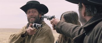 Movie still from “The Homesman” (2014), directed by Tommy Lee Jones – A man and a woman are holding guns; Medium shot, Over the shoulder angle