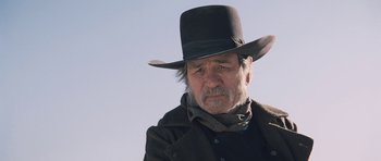 Movie still from “The Homesman” (2014), directed by Tommy Lee Jones – An older man wearing a black hat and a black coat; Close Up shot, Low angle