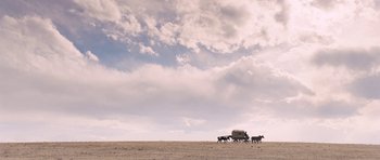 Movie still from “The Homesman” (2014), directed by Tommy Lee Jones – A horse drawn carriage traveling across a field; Extreme Wide shot, Low angle
